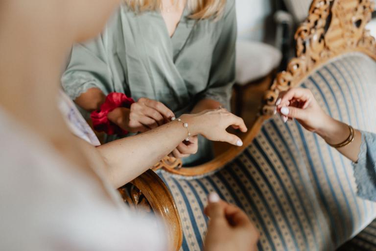 Braut wird Kette an Handgelenk angelegt