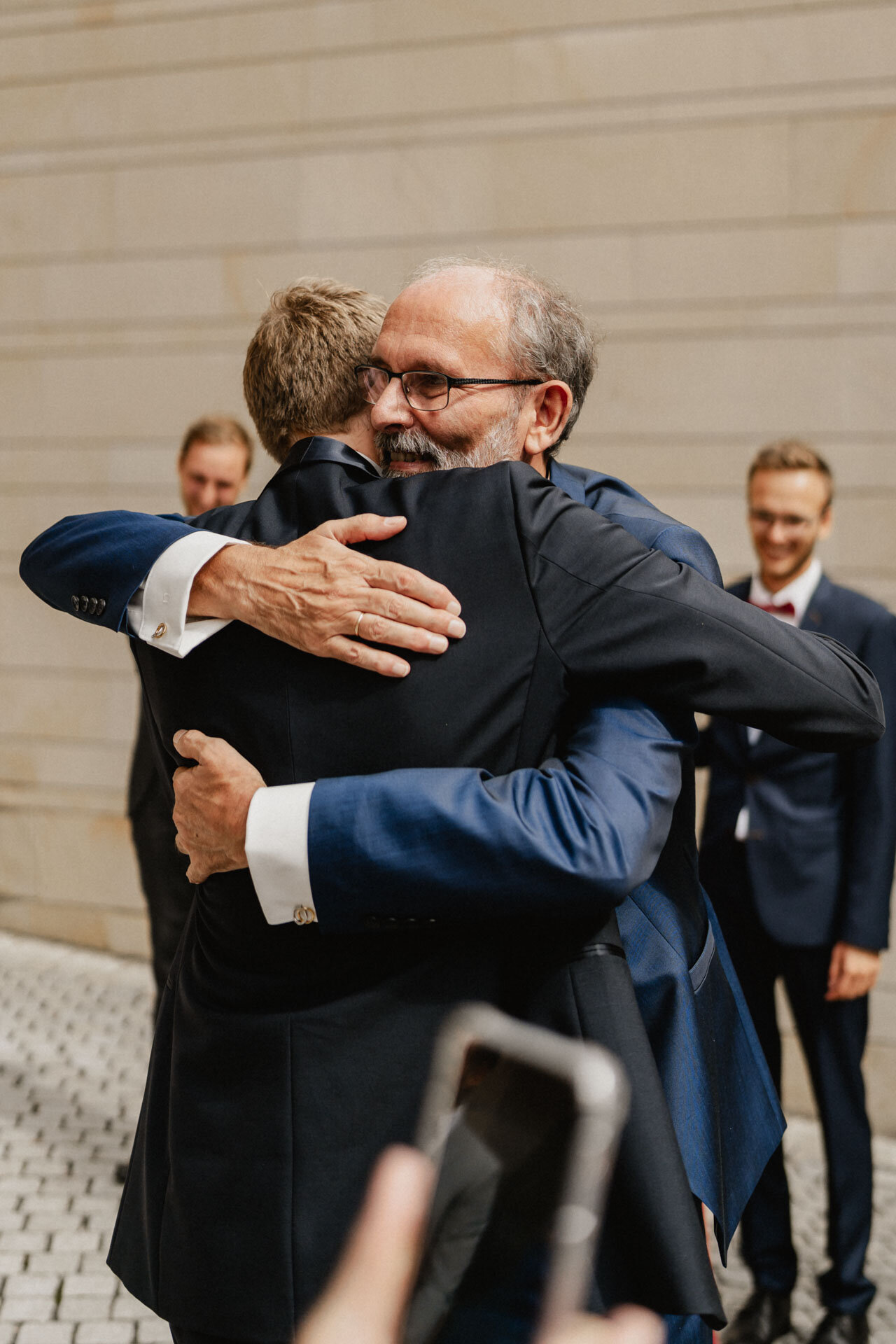 Vater umarmt Bräutigam während Hochzeit Alte Orangerie Schloss Rosenau