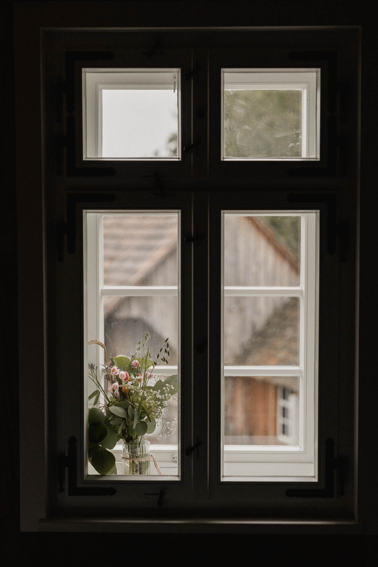 Fenster mit Blume drin mit dunklem Vordergrund bei Hochzeit auf dem Hochzeit auf dem Theurerhof Speßhardt