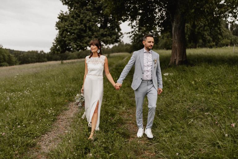 Brautpaar läuft Hand in Hand bei ihrer Hochzeit auf dem Theurerhof in Speßhardt