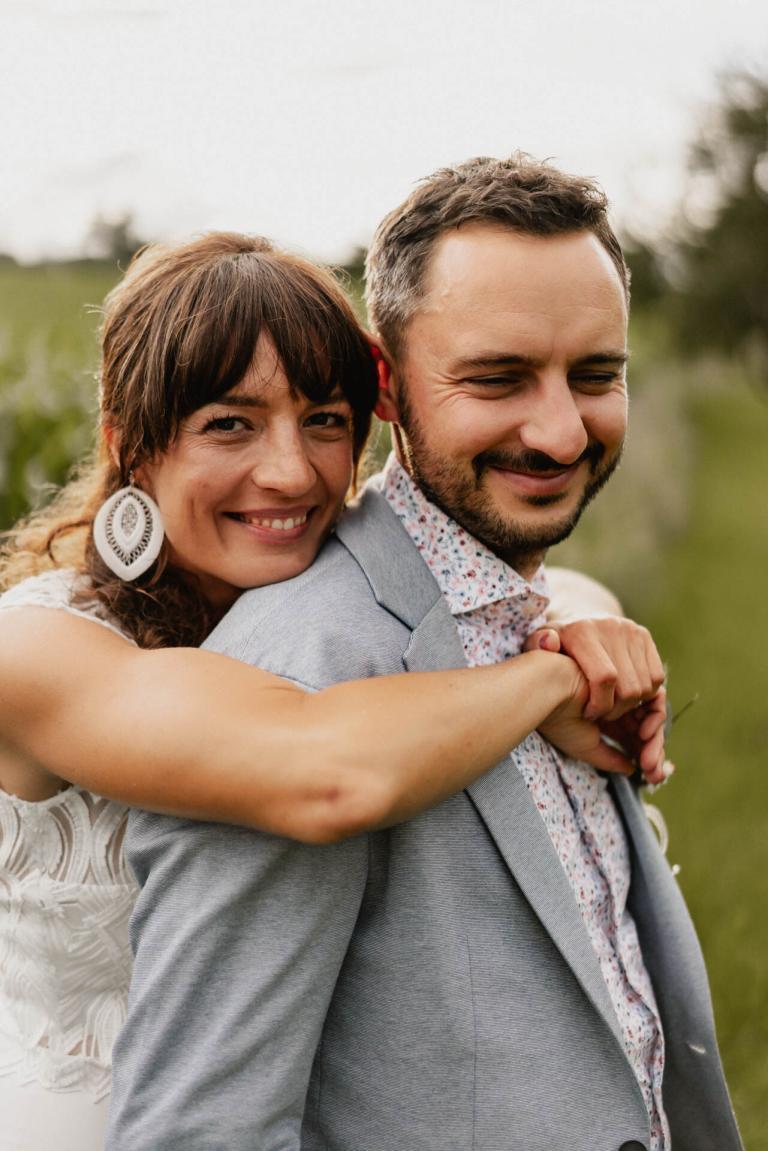 Braut umarmt Bräutigam von hinten bei ihrer Hochzeit auf dem Theurerhof Speßhardt