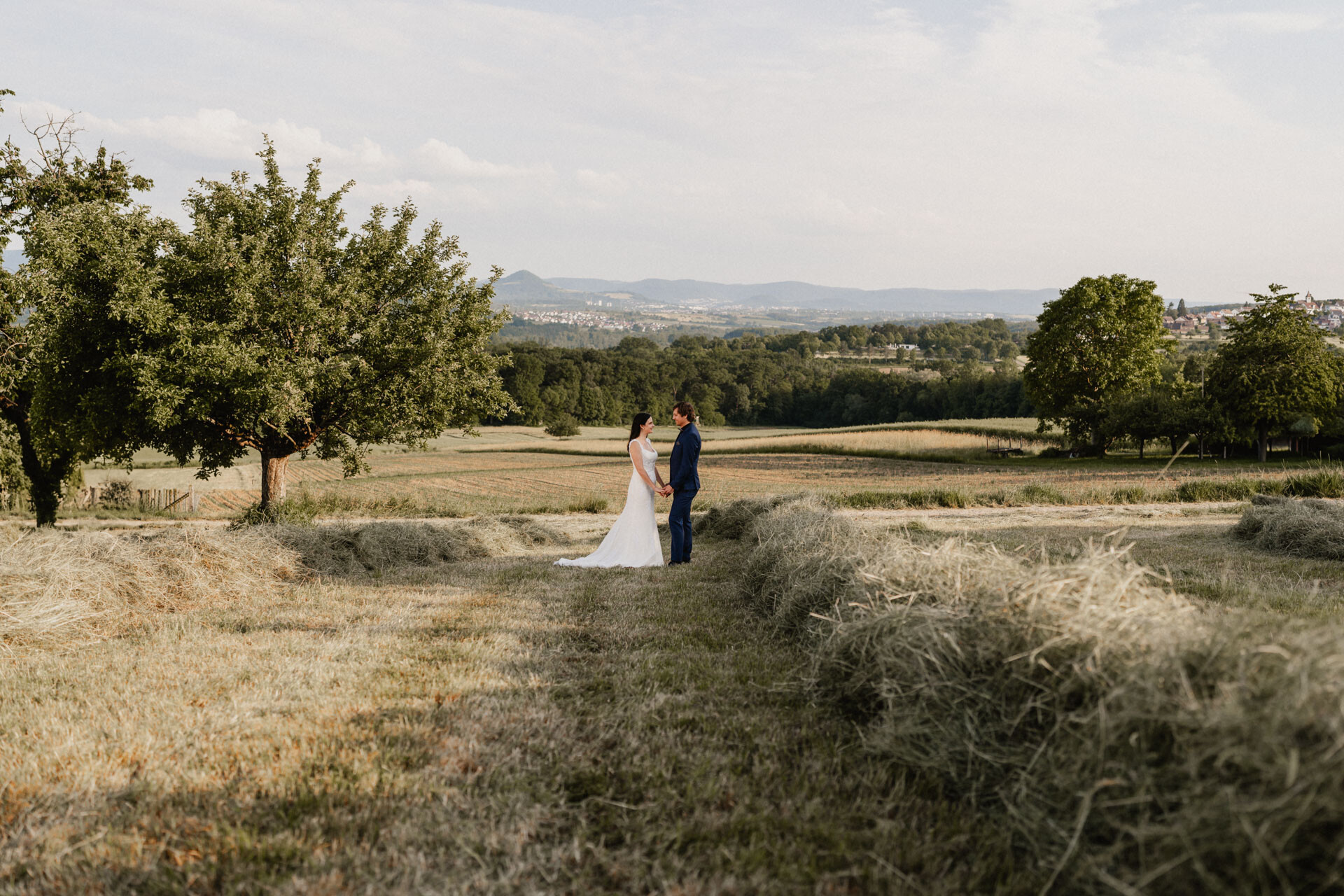 Brautpaar blickt sich an mit Landschaft im Hintergrund