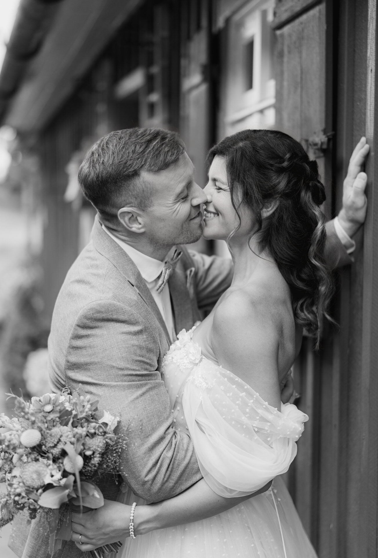 Bräutigam lehnt sich an Wand und küsst seine Braut für Hochzeitsfotograf Stuttgart